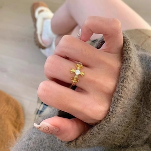 Vintage gold fleur-de-lis cross ring with zircon stone, worn on a model's hand