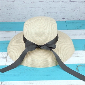 Close-up of beige woven straw sun hat with a decorative black silk bow ribbon