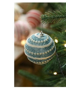 Close-up of blue glitter Christmas ball with white pearls hanging on a tree branch