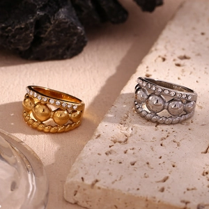 Macro shot of 18K gold and silver triple-layered rings with pavé rhinestones and twisted texture