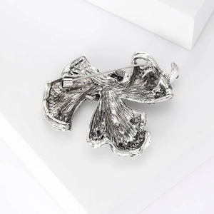 Detailed back view of vintage rhinestone bow brooch with silver textured metal and pin fastener