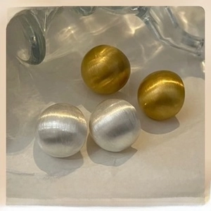 Detail of gold and silver ball earrings with brushed metal finish and matte texture