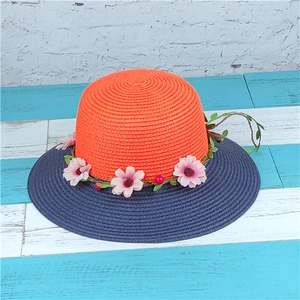 Detail of hand-woven straw hat crown with decorative floral garland and red berries