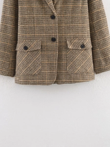 Detail eines Blazers mit Hahnentrittmuster, Frontknöpfen und Taschen in Braun