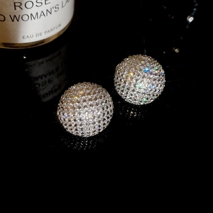 Macro shot of silver sphere earrings with sparkling pavé zircons on black background