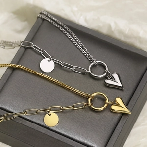 Dual-layer heart pendant necklace in gold and silver finish on a jewelry box