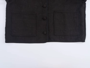 Close-up of black jacket detail featuring symmetrical large patch pockets and round buttons