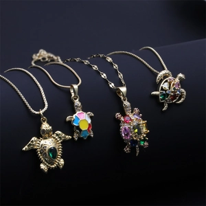 Detailed close-up of four luxury golden turtle necklaces with colorful cubic zirconia