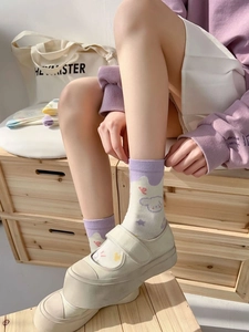Detail of cute purple cartoon socks with dog pattern worn with white Mary Jane shoes
