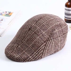 Detail shot of a brown plaid ivy cap with woolen texture on a white decorative table