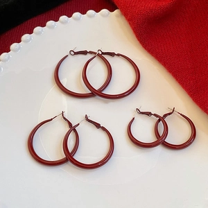 Three pairs of vintage red enamel hoop earrings in various sizes on a white display plate