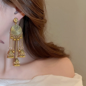 Macro shot of vintage style floral filigree earrings with dangling metal tassels and bells