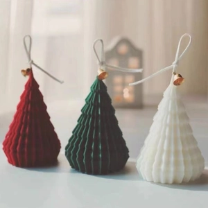 Three Christmas tree decorative candles in red, green, and white with gold bells