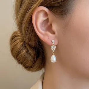 18k gold plated drop pearl earrings with sparkling zircon accents on an elegant female model