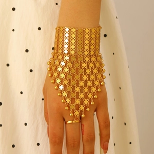 Dettaglio di un bracciale a anello vintage in metallo dorato con maglia geometrica
