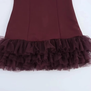 Dettaglio degli strati di tulle bordeaux e volant su un mini abito senza maniche