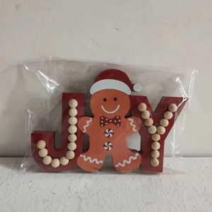 Close-up of wooden JOY sign with gingerbread man and red beads for Christmas decor