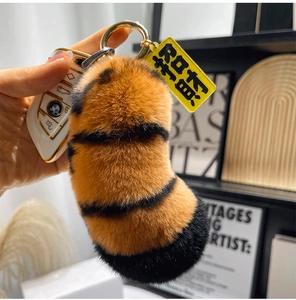Detail of plush tiger tail keychain with lucky charm and gold ring on BMW car key