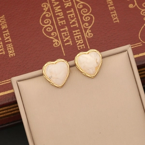 Detail of heart-shaped gold stud earrings with cream marble inlay on vintage display