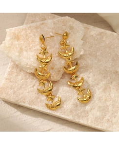 Detail of 18K gold star and moon drop earrings displayed on a white crystal stone