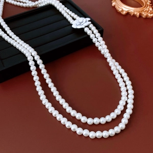 Detail of double-layer white glass pearl necklace with vintage camellia flower pendant