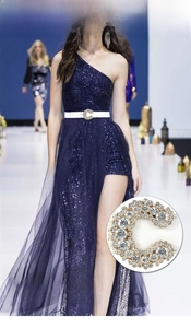 Detail of white leather belt with large C-shaped rhinestone buckle on a blue dress