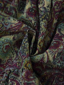 Detailed close-up of chiffon fabric with paisley pattern and metallic gold thread accents