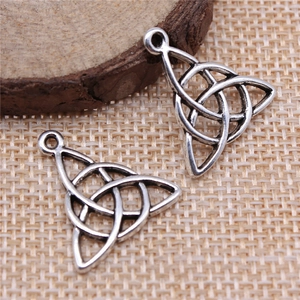 Antique silver Celtic knot charm pendants for DIY jewelry making on textured background