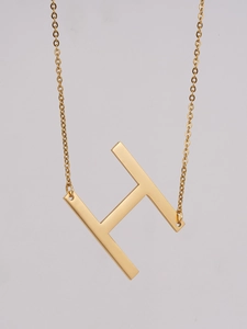Macro shot of 18K gold plated stainless steel letter H pendant on a dainty link chain