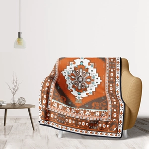 Detail of orange bohemian geometric flannel blanket draped over a modern sofa