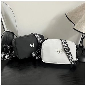 Detail of black and white nylon crossbody bags with silver butterfly and letter straps