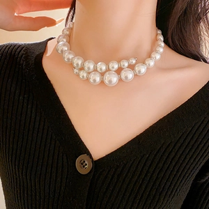 Close-up of double-layered faux pearl choker necklace worn with a black knit top