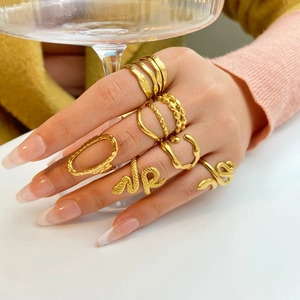 Detailed view of layered 18K gold snake ring and geometric bands on a hand
