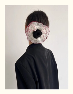Gros plan d'un grand chouchou en dentelle blanche avec bordure rouge sur un chignon
