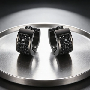 Macro detail of black matte stainless steel huggie earrings with inset sparkling crystals