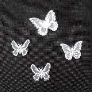 Detail of four white lace butterfly embroidery patches on black textured fabric