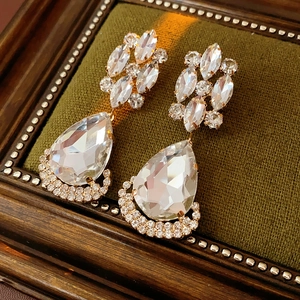 Macro view of vintage gold teardrop earrings with crystal rhinestones on green velvet