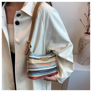 Detail of color-blocked woven shoulder bag with brown leather strap worn by a model