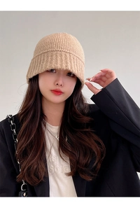 Detailed close-up of a warm beige knit bucket hat showing the thick ribbed texture