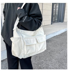 Detail view of white canvas crossbody bag with multi-pocket utility design and front flaps