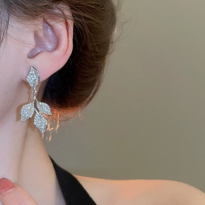 Detail of silver leaf tassel earrings with sparkling crystals worn by a model