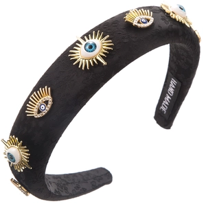 Close-up of padded denim headband with gold evil eye charms and rhinestone accents