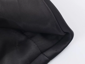 Dettaglio macro del tessuto satinato nero con trama a costine fini e cuciture precise