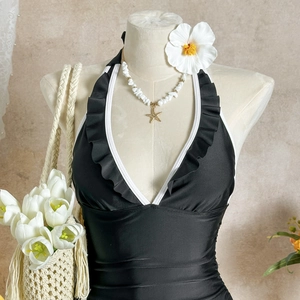 Detail of black one-piece swimsuit featuring white ruffle trim and deep V-neckline