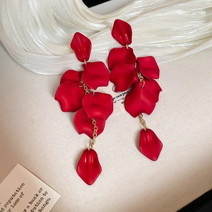 Detail of red floral fabric earrings with gold chain on a white silk ribbon background