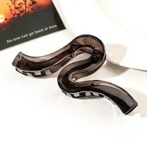 Detail of a large translucent brown S-shaped hair claw clip with a strong metal spring