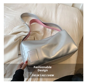 Detail der silbernen Metallic-Umhängetasche mit rosa Futter und rechteckigem Zieretikett