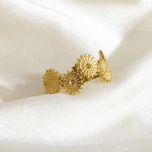 Elegant gold titanium steel daisy ring with circular texture on white silk background