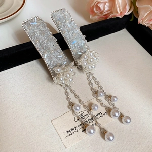 Macro detail of Chinese style floral hair clip with white pearls and crystal tassels