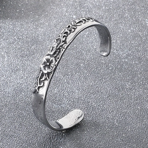 Detailed close-up of retro floral relief patterns on an antique silver titanium steel cuff